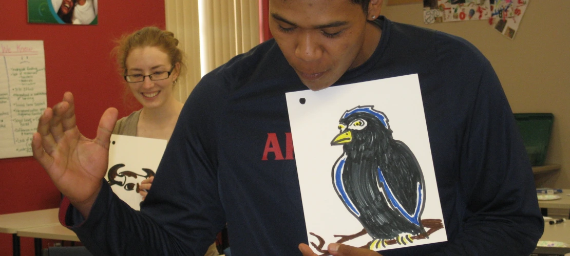 a male showing the drawing of a black bird